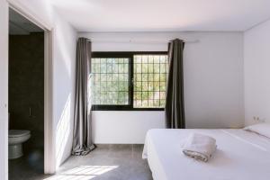 a bedroom with a white bed and a window at Villa Torres is a great villa only a 10 minute walk from the centre of Playa den Bossa in Ibiza Town