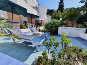un patio con 2 tumbonas y una sombrilla en Casa Acqua Marina Ponza, en Ponza