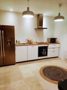 uma cozinha com um frigorífico de aço inoxidável e armários brancos em Maison de ville avec jardin, proche vignoble em Courthézon