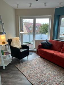 ein Wohnzimmer mit einem roten Sofa und einem Sessel in der Unterkunft Rosenhus 5 in Horumersiel