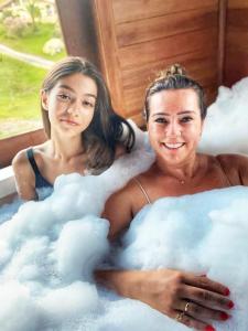 two women laying in a bathtub filled with clouds at Chalé Vista Das Araucárias in Urubici
