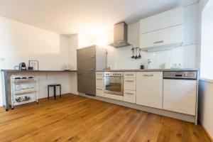 eine Küche mit weißen Schränken und Massivholzböden in der Unterkunft City Apartment DOWNTOWN in Bregenz