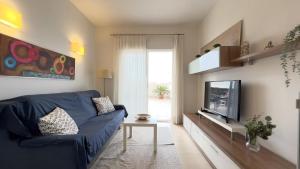 sala de estar con sofá azul y TV en La Ribera - terraza, piscina y playa, en San Javier