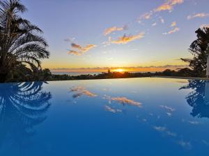an infinity pool with a sunset in the background at Le Colibri d'isa in Capesterre-Belle-Eau