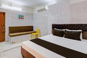 a bedroom with a large bed and a yellow chair at OYO Hotel Golden Pride in Shamshabad