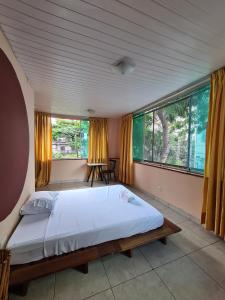 a bedroom with a large bed and large windows at Poente Hostel in Belo Horizonte