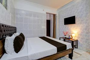 - une chambre avec un lit et une télévision murale dans l'établissement OYO Hotel Golden Pride, à Shamshabad