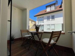 einen Balkon mit einem Tisch und Stühlen sowie ein Gebäude in der Unterkunft VINCENT Apartment in Bregenz mit Parkplatz in Bregenz