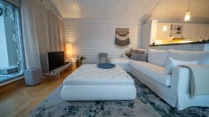 uma sala de estar com um sofá branco e uma televisão em Brensholmen Beach House em Tromsø