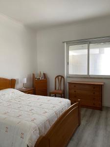 a bedroom with a bed and a dresser and a window at Casa em Charneca de Caparica in Charneca