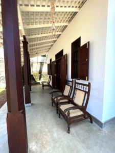 eine Reihe von Bänken auf einer Veranda in der Unterkunft Ceylon Little Paradise in Hikkaduwa