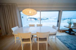 een eetkamer met een witte tafel en stoelen bij Brensholmen Beach House in Tromsø