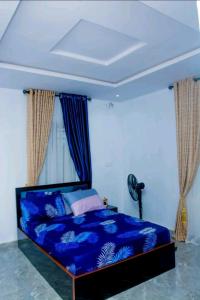 una camera con un letto blu e una finestra di Motalvin Court a Lagos