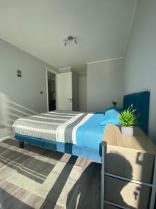 Un dormitorio con una cama azul y una mesa en Depto nuevo en brisas del sol, en Talcahuano