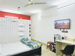 Habitación con cama, escritorio y TV en la pared. en Beautiful 1-Bed Studio in Dhaka, en Dhaka