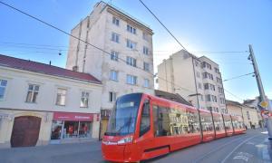 un tranvía rojo en una calle de la ciudad con edificios en Touch of history apartment, en Bratislava