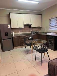 een keuken met een tafel en stoelen en een koelkast bij Seasons Court umhlanga 2bed Apt in Durban