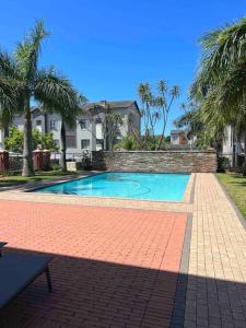 una piscina frente a una casa con palmeras en Seasons Court umhlanga 2bed Apt, en Durban