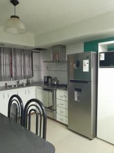 a kitchen with a stainless steel refrigerator and white cabinets at Tusvacaciones in Necochea