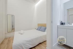 a white bedroom with a bed and a mirror at Cool And New Apt 3px entre Gran Via y Palacio Real in Madrid