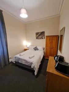 a bedroom with a bed and a dresser in it at Cathcart Place Rooms in Edinburgh