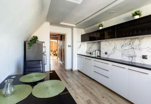 a kitchen with white cabinets and marble counter tops at Old Town Studio with Mezzanine in Gdańsk