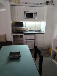 eine kleine Küche mit einem Tisch und einer Mikrowelle in der Unterkunft Altos Penitentes Lomas Blancas, dúplex in Uspallata