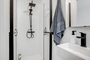 een witte badkamer met een douche en een wastafel bij Perfectly located cozy apartment in Kopenhagen