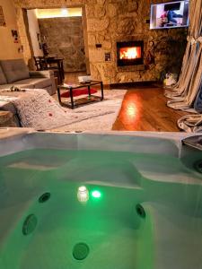 a hot tub in a living room with a fireplace at Casa Favo de Mel - Jacuzzi Privado in Arcos de Valdevez