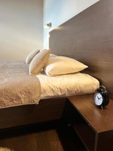 uma cama com almofadas e um relógio sobre uma mesa em AR GOLDEN HOUSE em Košice