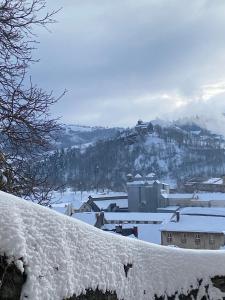 una ciudad cubierta de nieve con una montaña en el fondo en COSY B&B en Murat