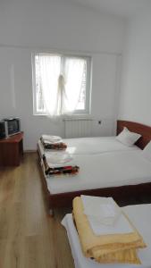 a white bedroom with two beds and a window at Семеен хотел Узана in Gabrovo