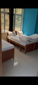 two beds in a room with two windows at haridwar jmg and kedarnath Hotel in Haridwār