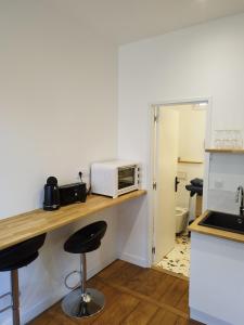 une cuisine avec un comptoir, un four micro-ondes et des tabourets dans l'établissement ROMANESCO, à Rennes
