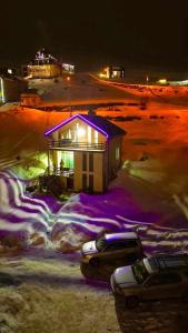 una pequeña casa con luces moradas en la nieve en Cottage in Gudauri, en Gudauri
