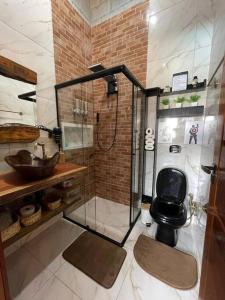 a bathroom with a shower with a black toilet at recanto do sossego. in Sinop