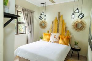 una camera da letto con un letto bianco con cuscini gialli di Pumbaa Wildlife Park & Accommodation a Nelspruit