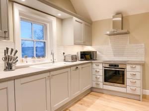 a kitchen with white cabinets and a sink and a window at The Annexe - KG Retreats in Ketton