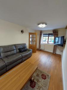 a living room with a leather couch and a flat screen tv at Dobcross Close in Manchester