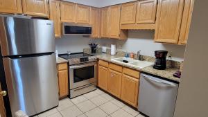 a kitchen with wooden cabinets and a stainless steel refrigerator at Cozy Flagstaff Condo in Flagstaff