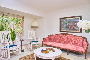 ein Wohnzimmer mit einem rosa Sofa und 2 Stühlen in der Unterkunft Apartahotel Fiorentina Boutique in Medellín