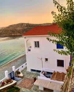 a white house on the beach with the ocean at Aegean Aura Apartment II in Kalymnos