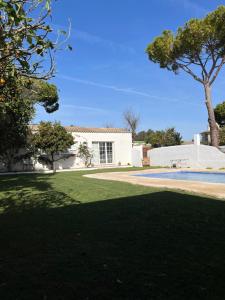 a white house with a tree and a yard at Chalet Ciudad Ducal con piscina y jardin in El Puerto de Santa María