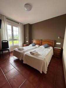 1 dormitorio con 1 cama grande con sábanas blancas en Hotel Restaurante el Fornon, en Novellana