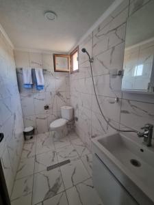 a white bathroom with a toilet and a sink at Къща за гости Люляк in Lyulyakovo