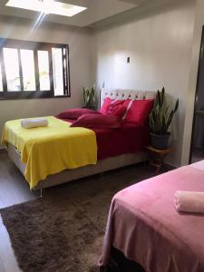 1 Schlafzimmer mit 2 Betten mit roter und gelber Bettwäsche in der Unterkunft Casa Aconchego dos Canyons in Praia Grande