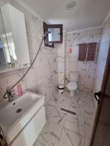 a white bathroom with a sink and a toilet at Къща за гости Люляк in Lyulyakovo