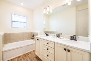 a bathroom with a tub and a sink and a bath tubermottermott at Margaritaville Cottages Orlando by Rentyl in Orlando