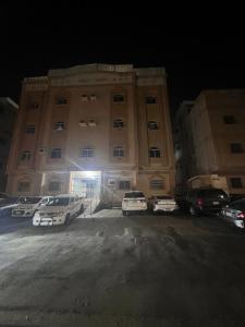 un gran edificio con coches estacionados frente a él en شقة الغامدي en Al Jāmi‘ah
