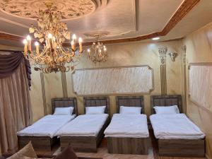 Cette chambre comprend deux lits et un lustre. dans l'établissement شقة الغامدي, à Al Jāmi‘ah